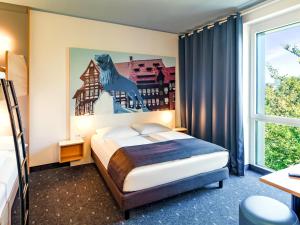 1 dormitorio con 1 cama con un caballo en la pared en B&B Hotel Braunschweig-City, en Brunswick