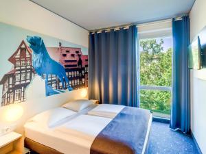 a hotel room with a bed and a window at B&B Hotel Braunschweig-City in Braunschweig