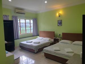 duas camas num quarto com paredes verdes em Borneo Gaya Lodge em Kota Kinabalu