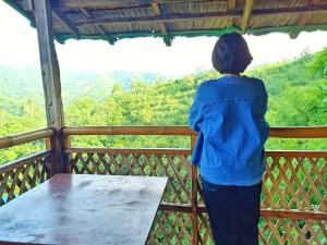 Una mujer parada en un balcón con vistas a las montañas en MIRA AgroPark en Tanay