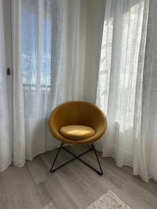 a yellow chair sitting in front of a window at T3 Moulin à vent proche UPVD in Perpignan