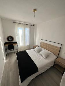 a bedroom with a black and white bed and a desk at T3 Moulin à vent proche UPVD in Perpignan