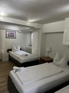 a hotel room with two beds with white sheets at GZ Hostel Bonn in Bonn