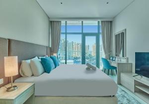 a bedroom with a large white bed and a desk at First Class Apartments in Seven Palm with direct Access to the West Palm Beach and Nakheel Mall in Dubai