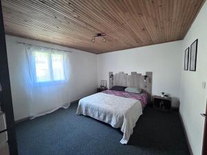 1 dormitorio con cama y techo de madera en La Guitoune, en Mane