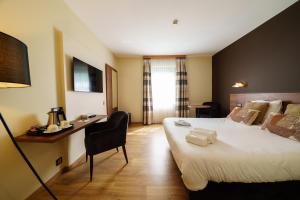 a hotel room with a large bed and a desk at Hotel Les Jardins De La Molignée in Dinant