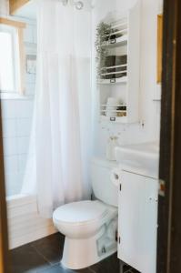 a white bathroom with a toilet and a sink at Le Grizzli Orford in Orford