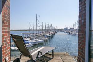 a chair sitting on a balcony next to a marina at Ostsee - Ferienhaus Nr 57 "360 Grad & Meer" im Strand Resort in Heiligenhafen