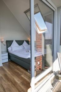 ハイリゲンハーフェンにあるOstsee - Ferienhaus Nr 57 "360 Grad & Meer" im Strand Resortのベッドルーム1室(ベッド1台、ガラス窓付)