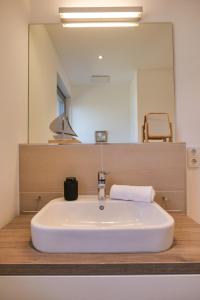 a bathroom with a white sink and a mirror at Ostsee - Ferienhaus Nr 57 "360 Grad & Meer" im Strand Resort in Heiligenhafen