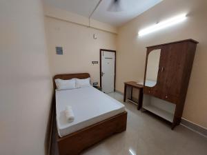 a small bedroom with a bed and a mirror at Hotel Hari Gayatri Regent in Guwahati