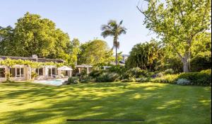 a yard with a large lawn with trees and a house at Garden Cottage - Leafy Constantia Guest House in Cape Town