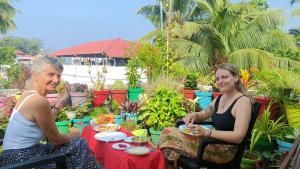 deux femmes assises à une table dans un jardin dans l'établissement Nest, à Cochin