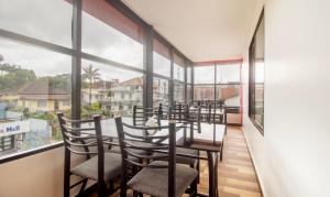 a room with a table and chairs and windows at Treebo Trend Elite Plaza 700 Mtrs From Madikeri Fort in Madikeri