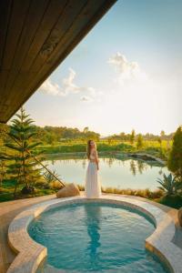 una mujer vestida de novia parada junto a una piscina en Pine Village CNX, 
