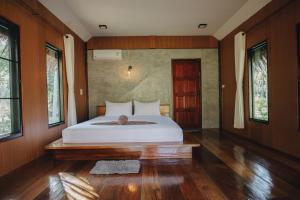 1 dormitorio con 1 cama blanca grande, suelo de madera y ventanas en COCO Canopy Boutique Resort, en Ko Jum