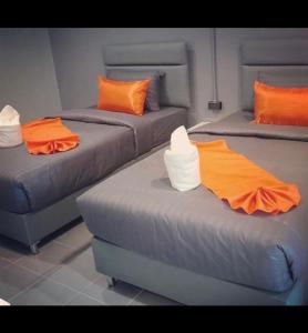 3 camas con almohadas de color naranja y blanco en una habitación en เสาวลักษณ์ เรสซิเด้นท์, en Khon Kaen