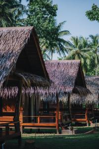 un resort con tetto di paglia, panchine e palme di COCO Canopy Boutique Resort a Koh Jum