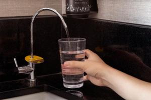 a person holding a glass of water in a sink at Hotel Mi Rochor in Singapore
