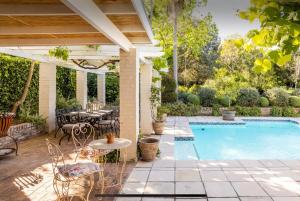 an outdoor patio with a table and chairs and a pool at Fig Tree Cottage - Leafy Constantia Cottages in Cape Town