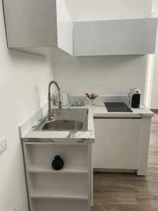 a white kitchen with a sink and a counter at Residenza da Mimi in Ercolano