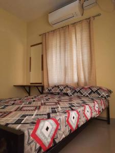 a bedroom with a bed and a window with a curtain at 2 BHK house, on premise parking, upto 10 guests in Mangalore