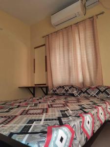 a bedroom with a bed and a window with a curtain at 2 BHK house, on premise parking, upto 10 guests in Mangalore