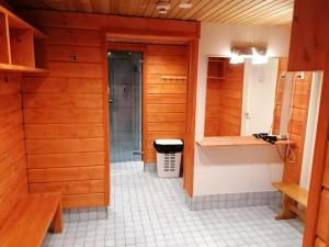 baño con paredes de madera y suelo de baldosa blanca en Vuosselin Helmi Apartments, en Ruka