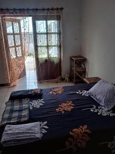 a bedroom with a bed with a blue blanket and a window at Beach and sunset villa in Mboro