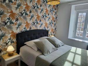 1 dormitorio con 1 cama y papel pintado con motivos florales en Gîte les Embruns, en Pirou