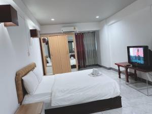 1 dormitorio con 1 cama blanca y TV en โรงแรมวินบางนา Win Bangna Hotel, en Bangna