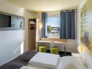 um quarto com uma cama, uma secretária e uma janela em B&B Hotel Braunschweig-Nord em Braunschweig