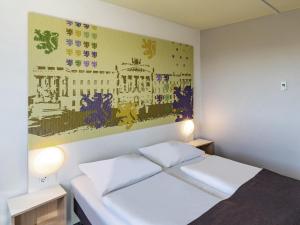 ein Schlafzimmer mit einem Bett und einem Wandgemälde in der Unterkunft B&B Hotel Braunschweig-Nord in Braunschweig