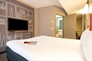 a hotel room with a bed and a tv at ibis Geneve Centre Lac in Geneva
