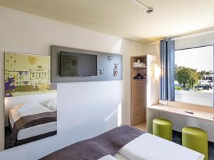 ブラウンシュヴァイクにあるB&B Hotel Braunschweig-Nordのベッド1台、壁掛けテレビが備わるホテルルームです。
