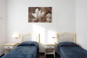 2 Betten in einem Zimmer mit 2 Tischen und einem Gemälde in der Unterkunft Il Gabbiano in Albissola Marina