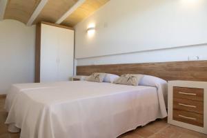 1 dormitorio con 1 cama blanca y 2 almohadas en Santolina - Casa Rural en l'Ampolla con piscina privada, jardín y barbacoa - Deltavacaciones, en L'Ampolla