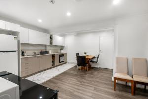 a kitchen with white cabinets and a table and chairs at Spacious Sandy Bay Apartment in Sandy Bay