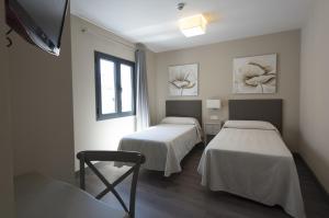 a hospital room with two beds and a television at Hostal Emeritae in Mérida