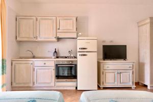 uma cozinha com um frigorífico branco e uma televisão em Apartments with air conditioning in Orosei em Orosei