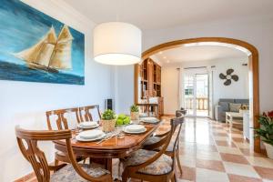 a dining room with a table and chairs and a painting of a boat at Villa Marques by Villa Plus in Cala'n Porter
