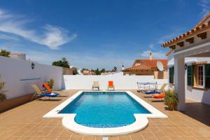a swimming pool on a patio with chairs and a house at Villa Maria Del Mar by Villa Plus in Cala'n Porter