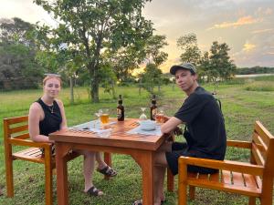 a man and a woman sitting at a wooden table at Saffron Lake Yala in Tissamaharama