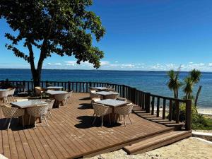 una terrazza in legno con tavoli e sedie accanto all'acqua di Cebu Cozy Ocean View 1BR,17th,private beach,pool,Wifi,Mactan a Mactan