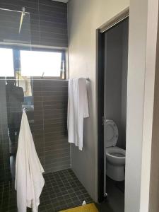 a bathroom with a toilet and a shower with towels at The Blues in Pretoria