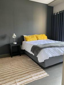 a bedroom with a bed with yellow pillows and a rug at The Blues in Pretoria
