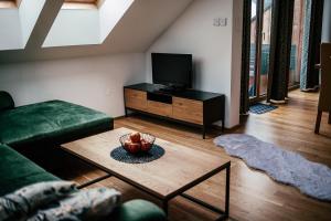 a living room with a green couch and a television at Alpenhotel & Aparthotel Lanz in Hohentauern