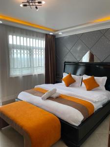 ein Schlafzimmer mit einem großen Bett mit orangefarbenen Kissen in der Unterkunft Lux Suites Nakuru VIP Suites in Nakuru
