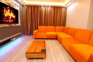 ein orangefarbenes Sofa im Wohnzimmer mit einem TV in der Unterkunft Lux Suites Nakuru VIP Suites in Nakuru
