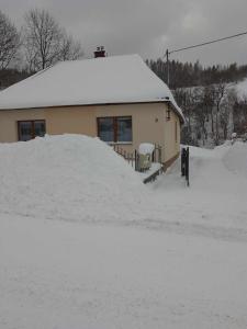 a house with a mound of snow in front of it at Domek in Reľov